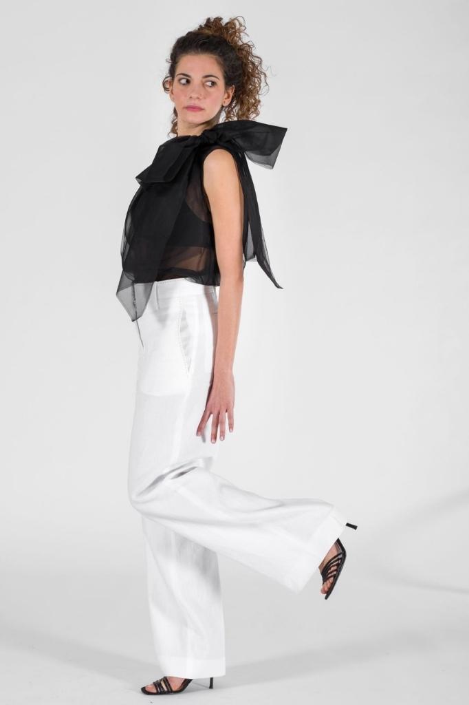 Donna con indosso pantalone lungo bianco e top nero con dettaglio sulla spalla - collezione PE 2020